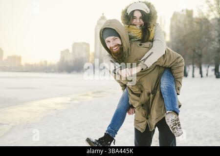 Thema Neujahr Weihnachten Stimmung Winter Schnee Feiertage Valentinstag. Junge kaukasische Paar Liebhaber Freude, Lachen Wasser im Stadtpark. Mann hae Stock Photo