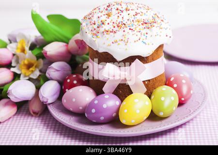 Easter cake and colorful polka dot eggs on the plate and flowers on the foreground Stock Photo