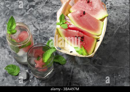 Wassermelone Cocktail. Wassermelone Cocktail mit Minze und Scheiben Wassermelone auf einer grauen Betonoberflaeche. Blick von oben. Platz kopieren Stock Photo