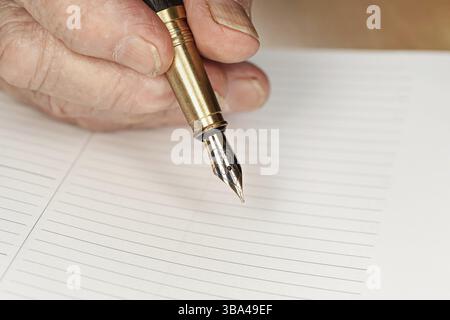 Gold coloured fountain ink pen in senior woman hand about to write something on empty daily planner page, closeup detail, Liptovsky Hradok, Slovakia, Stock Photo