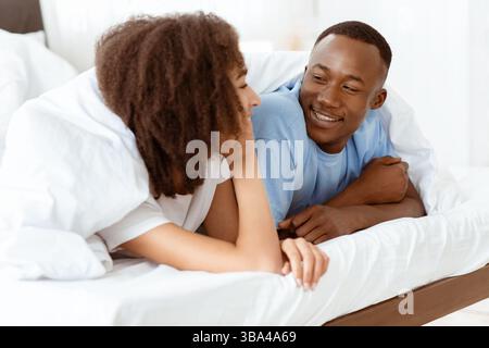 Young relaxed beautiful couple lying in bed at morning at weekend Stock Photo