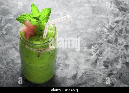Tropical cocktail. Smoothie with mint, slices of watermelon and ice cubes on a gray concrete surface. View from above. Copy space Stock Photo