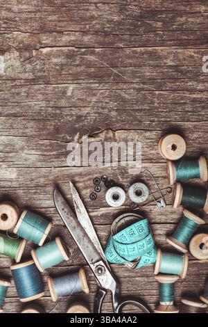 Retro scissors, textile and sewing threads on the wooden table Stock Photo