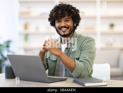 Cheerful indian guy programmer posing at workdesk Stock Photo