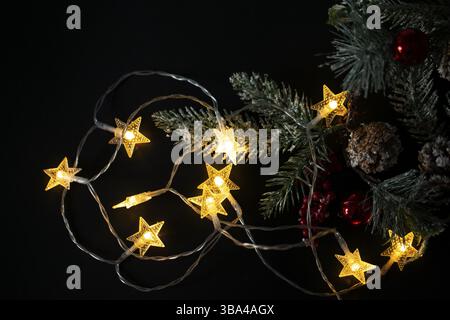 Christmas background with lights and a Christmas tree branch. Christmas lights from a garland on a black background Stock Photo