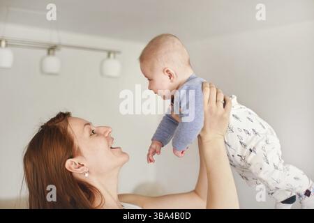 Mother playing with his infant son, holding him in her hands above her head, looks like fly, Ruzomberok, Slovakia, Europe Stock Photo