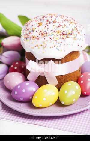 Easter cake and colorful polka dot eggs on the plate and flowers on the foreground Stock Photo