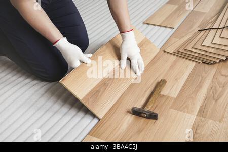 Man installing laminated floor, detail on wooden tile being fitted, over white foam base layer, Liptovsky Mikulas, Slovakia, Europe Stock Photo
