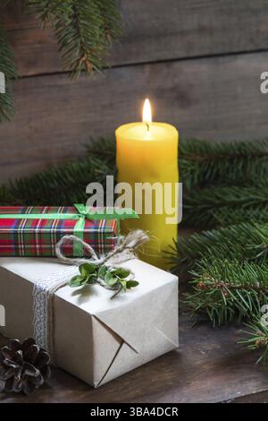 Christmas gifts and lighted candle with christmas tree and cones on wooden background Stock Photo