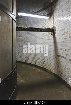 Interior of Greenwich foot tunnel, dirty grunge walls and floor in narrow corridor lit by neon light, London, United Kingdom, Europe Stock Photo