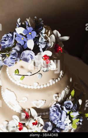 Three-storied wedding cake with violet flowers on a glass stand Stock Photo