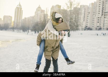Thema Neujahr Weihnachten Stimmung Winter Schnee Feiertage Valentinstag. Junge kaukasische Paar Liebhaber Freude, Lachen Wasser im Stadtpark. Mann hae Stock Photo