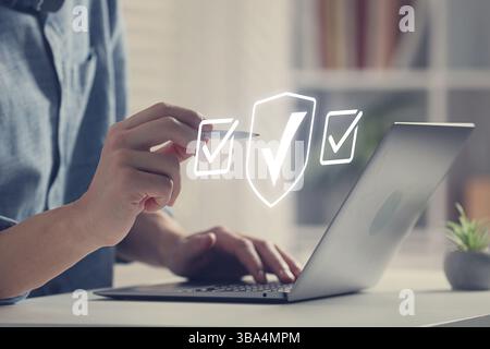 Approved. Man using laptop and touching virtual screen with check marks at table, closeup Stock Photo