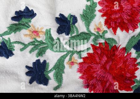 A piece of white cotton fabric with embroidered bright flowers Stock Photo