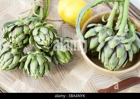 Two artichoke bouquets on kitchen table among some kitchen items. Top view Stock Photo