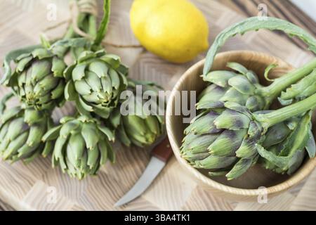 Two artichoke bouquets on kitchen table among some kitchen items. Top view Stock Photo