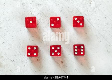 Overhead shot - red translucent playing dices showing all numbers from 1 to 6 on white concrete board, Liptovsky Hradok, Slovakia, Europe Stock Photo