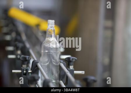 A long row of glass bottles on a conveyor belt. Production of alcoholic beverages Stock Photo