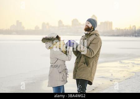 Young couple cheerfully flounders in snow. Between comic fight. Happy young couple hugs in winter snowy woods. Romantic lifestyle men and women in lov Stock Photo