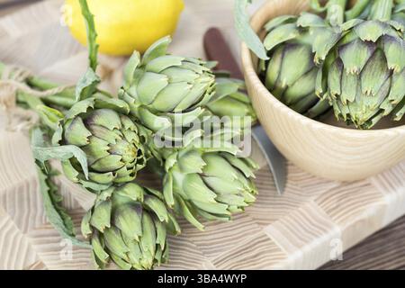 Two artichoke bouquets on kitchen table among some kitchen items. Top view Stock Photo