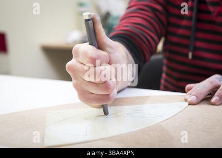 April 16, 2017. Ukraine, Kiev.men's hands close-up cut glass on the stencil with a metal glass cutter Stock Photo
