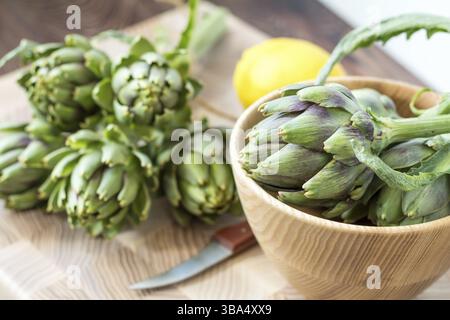 Two artichoke bouquets on kitchen table among some kitchen items Stock Photo