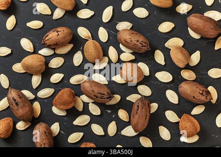 Whole almonds, pecan nuts and pumpkin seeds mixed on black marble like board, view from above, Liptovsky Hradok, Slovakia, Europe Stock Photo