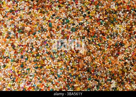 Vivid surface full of mixed gems, pearls, and beads. Decorative stones in rich hues create a shiny and artistic natural background Stock Photo