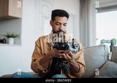 Handsome engineer student working on robot project at home. Stock Photo