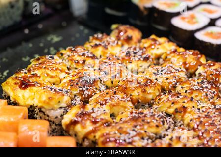 On the table, you will find an assortment of various types of sushi arranged beautifully and ready to be enjoyed by everyone present Stock Photo