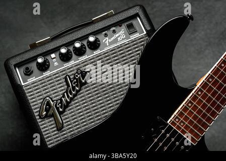 Sound amplifier Fender Frontman 10G and a black electric guitar over black background. Illustrative editorial Stock Photo