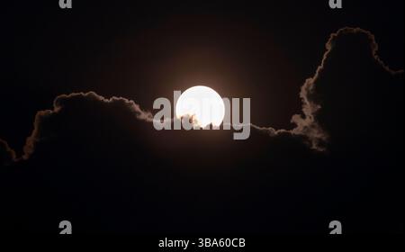 A bright full moon lights up the passing clouds on a Spring evening over Worcestershire, England. Stock Photo
