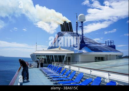Yellow smoke from exhaust funnel of cruise ship LOUIS CRISTAL in navigation in Aegean Sea, Greece - 2025: sold to Alang Indian demolition scrapyard Stock Photo