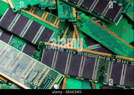 Various computer memory modules are piled on a green circuit board, showcasing technology. Stock Photo