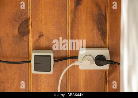 Socket and switch on a wooden wall outside, household plastic sockets Stock Photo