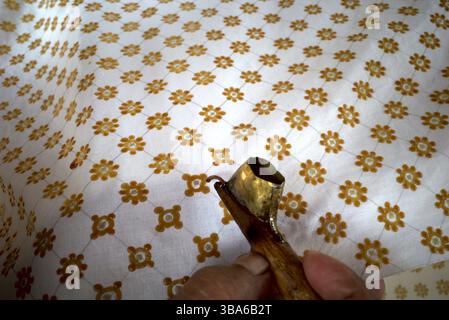 The process of making written batik, a traditional Indonesian clothing, uses canting to make lines and the dots on the fabric. Stock Photo