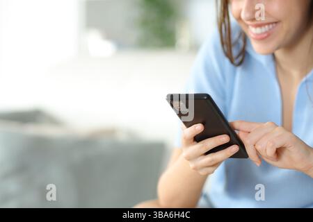Close up of a happy woman holding and using smart phone at home Stock Photo