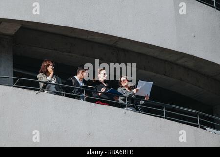 Multicultural business team analyzing data on office balcony Stock Photo