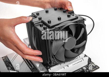 A person is installing a large black tower-style CPU cooler Stock Photo