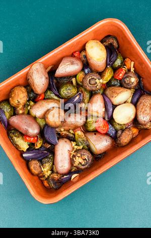 Roasted mushrooms, Brussels sprouts, and potatoes, garnished with onion on a baking dish. Oven baked vegetables. Stock Photo