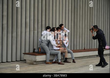 Groomsmen gather around the groom for a playful group photo in the West Kowloon Art Park Stock Photo