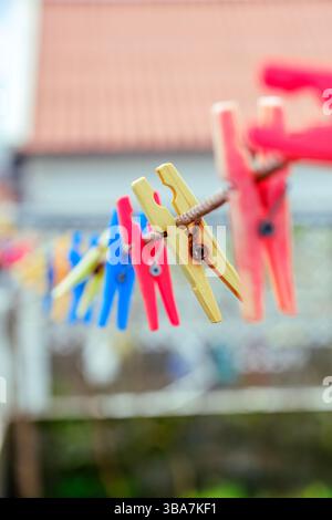 Colorful Plastic Clothespins Hanging on a Clothesline. Illustrates everyday laundry tasks and vibrant household items. Stock Photo