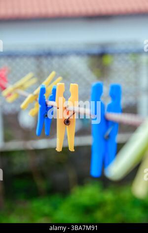 Colorful Plastic Clothespins Hanging on a Clothesline. Illustrates everyday laundry tasks and vibrant household items. Stock Photo