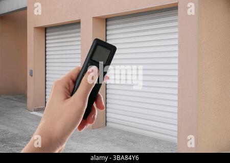 Woman using remote to control roller door outdoors, closeup Stock Photo