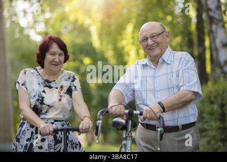 Happy elderly couple with a bicycle. Handsome man and woman seniors. Husband and woman in old age for a walk Stock Photo