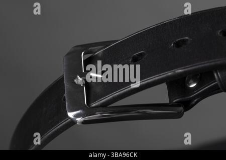 Part of a black leather belt with a metal buckle Close-up on a grey background Stock Photo