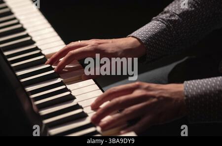 Hands playing piano in a dark theatre blouse white and black keys amsterdam Stock Photo