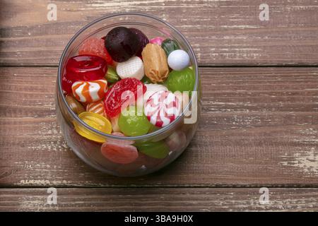 Sweets in a glass on a wooden background. Multicoloured caramel. Sweets Stock Photo