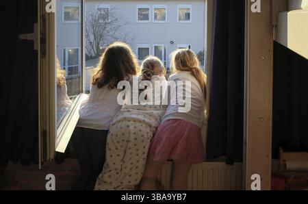 Girls watching out the window at a cat on the roof Stock Photo