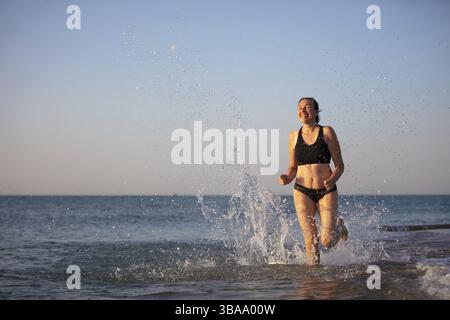 A middle-aged woman walks along the shore. Doing sport on the sea Stock Photo